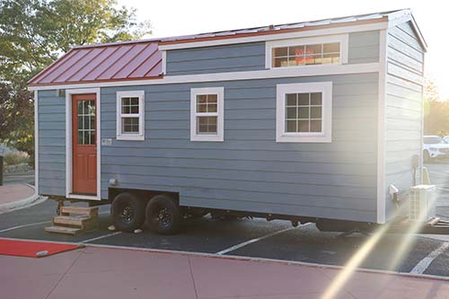 Blue Tiny House with white trim, red door, and red roof