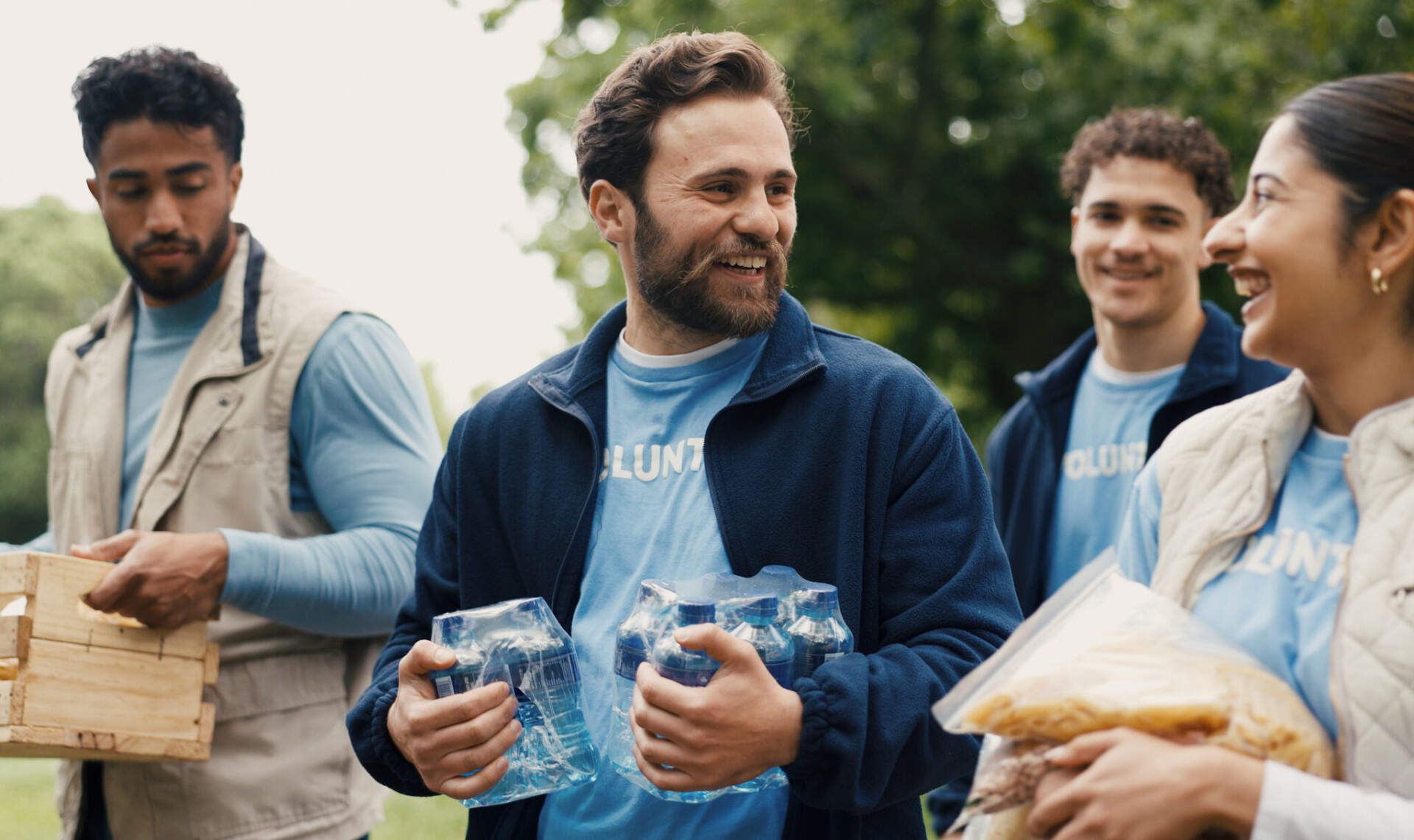 Volunteers in matching blue shirts handing out water and food at an outdoor event