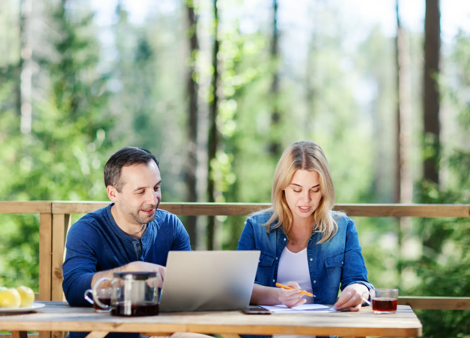 A couple working on a laptop together on an outdoor deck