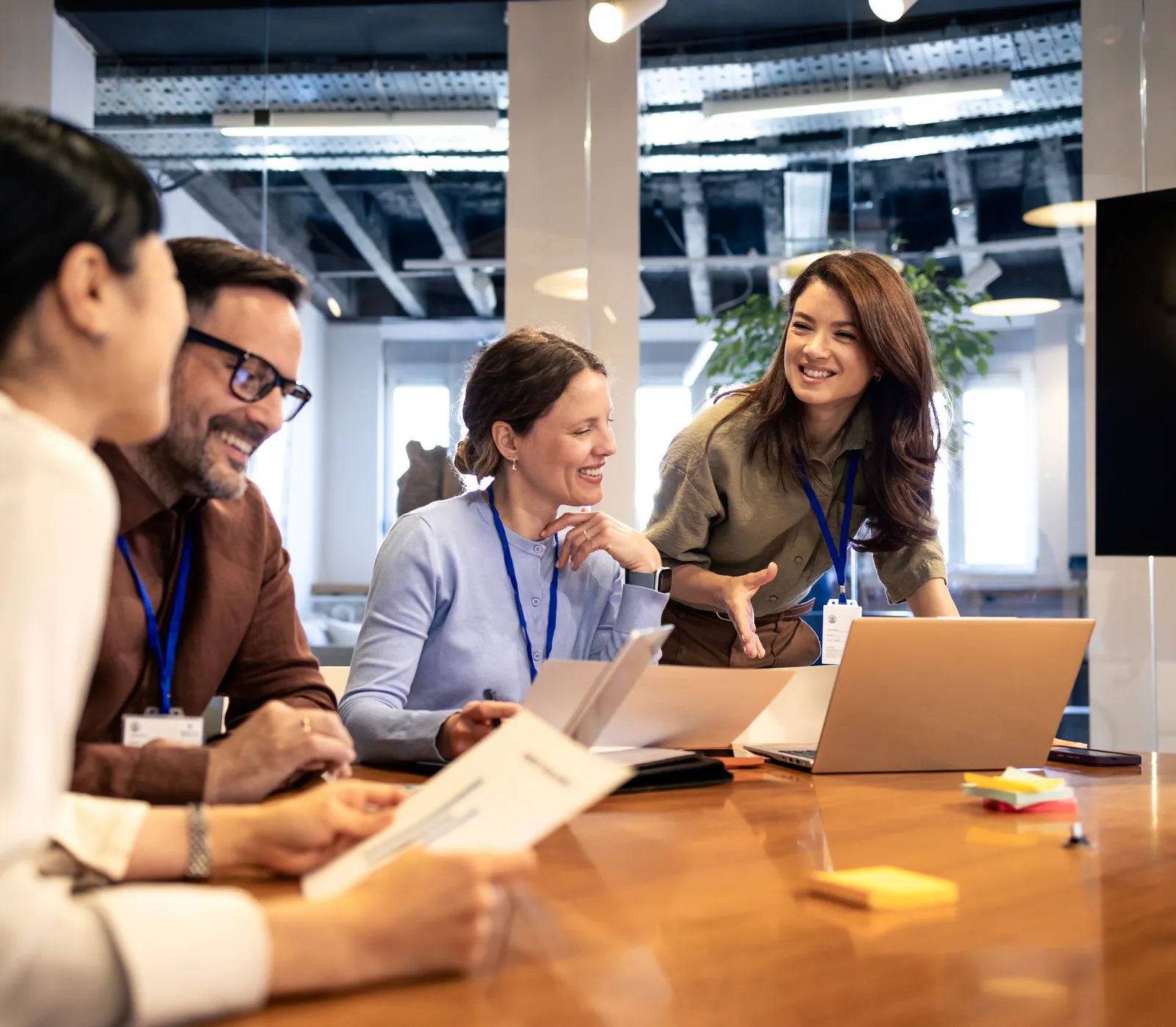 Colleagues smiling and collaborating around a table with laptops