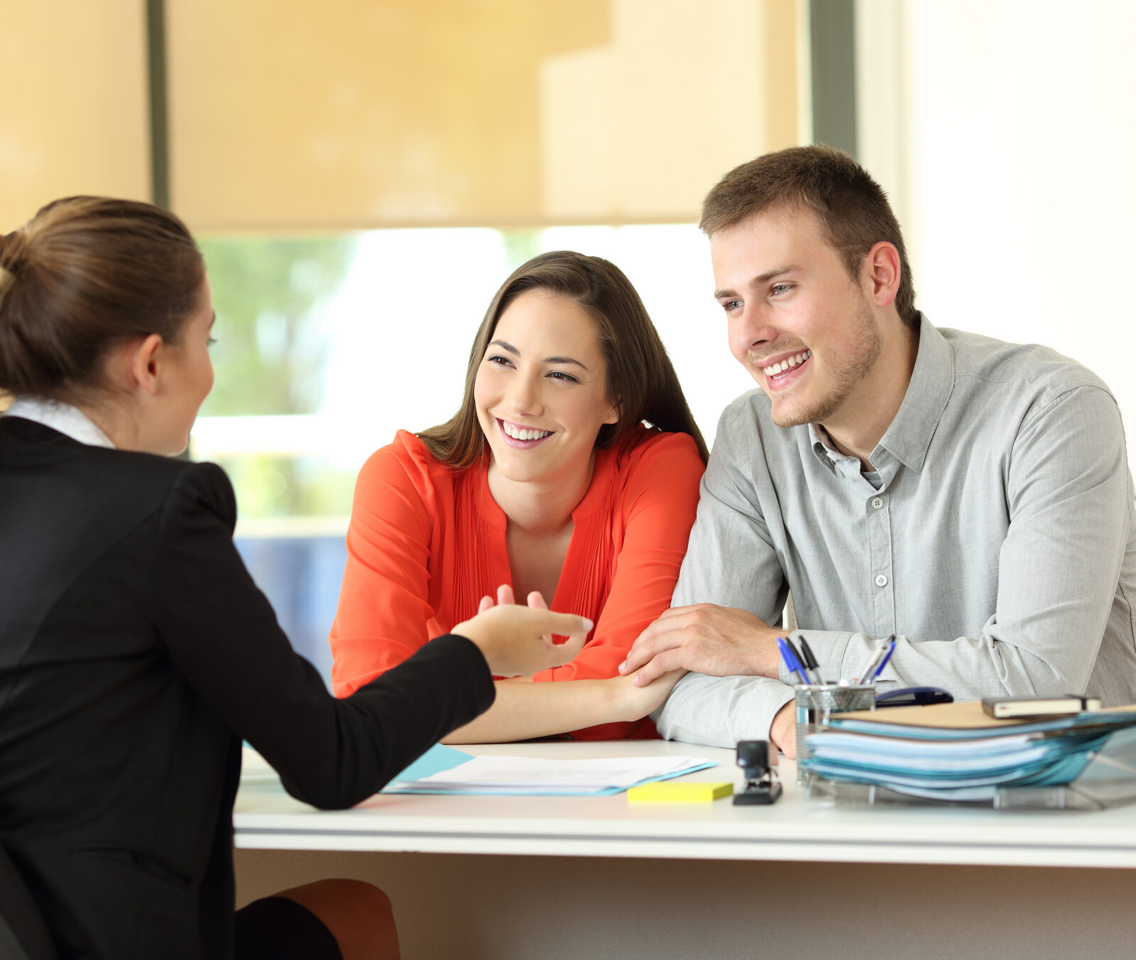 An office worker talking with a smiling couple at a desk