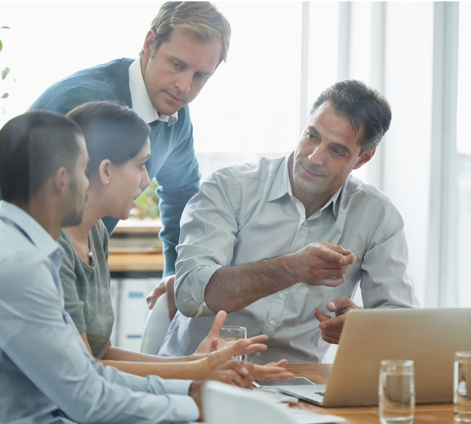 A team of colleagues discussing work around a laptop