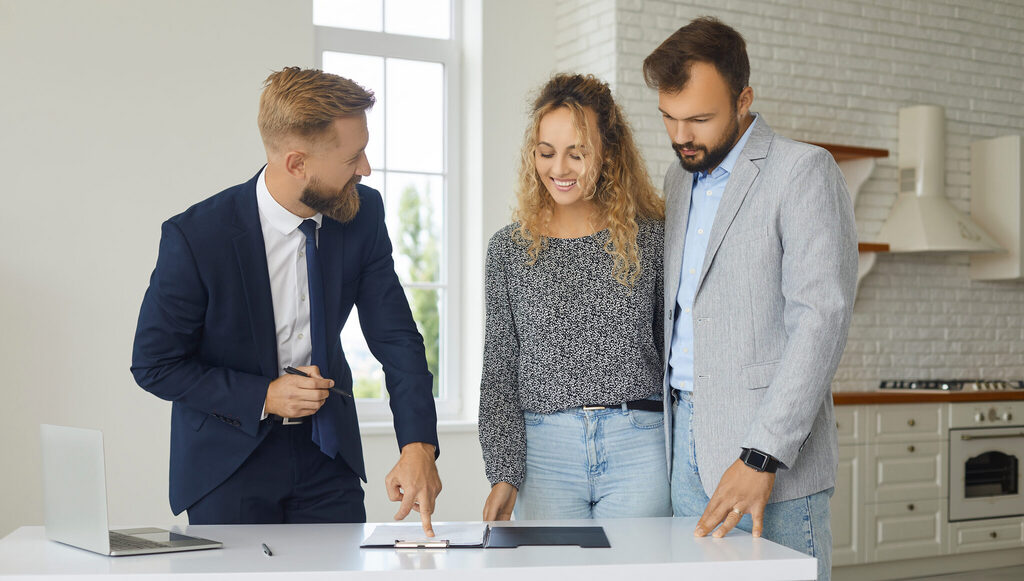 Real estate agent reviewing a contract with a couple at a table in a bright home