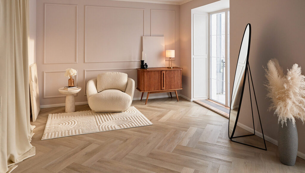Bright staged living room with a cream armchair, side table and herringbone floor