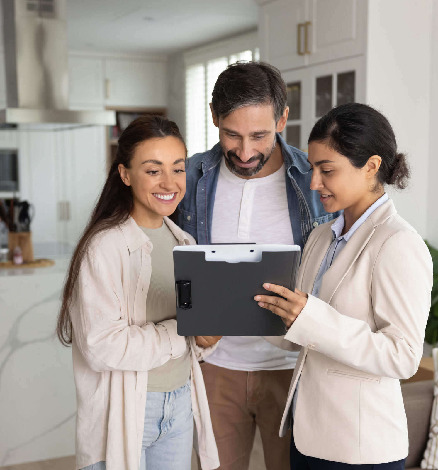 Real estate agent reviewing a clipboard with a couple in a bright home