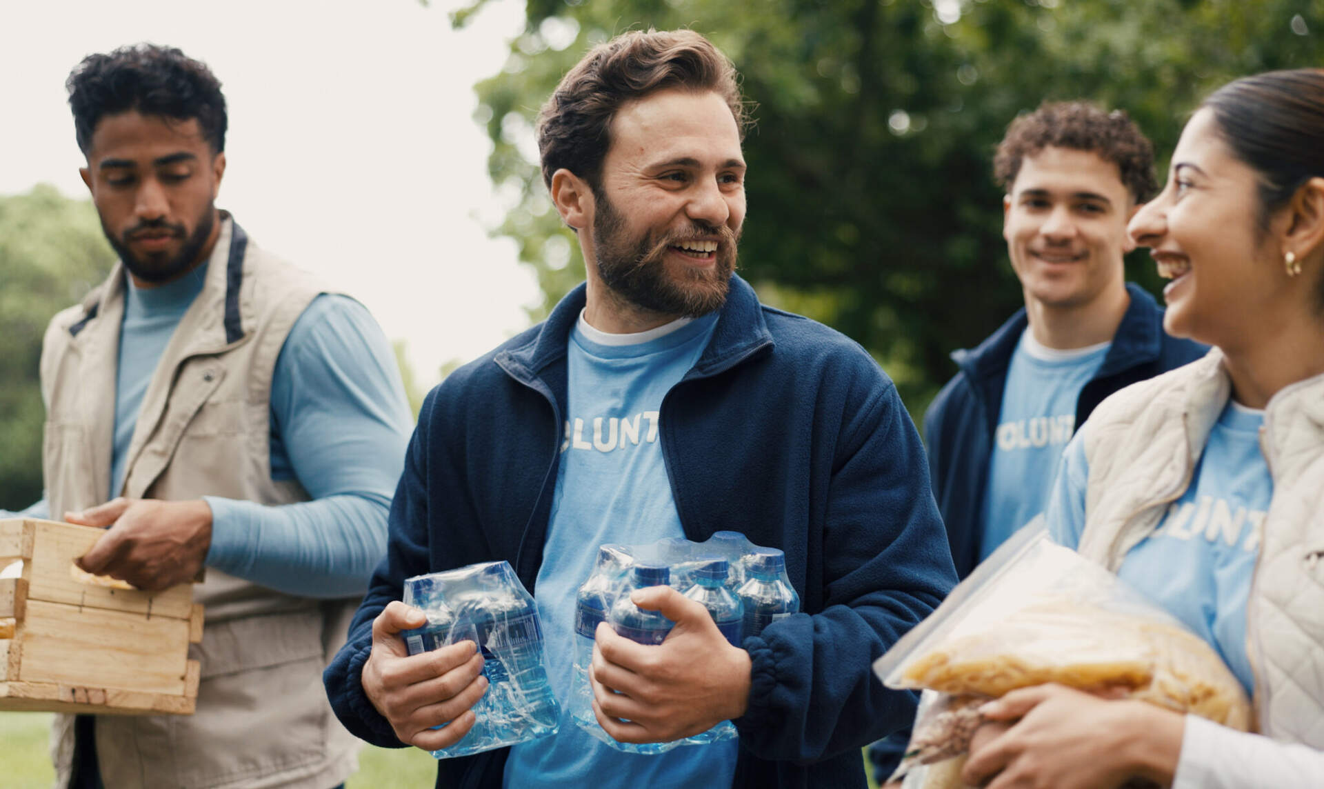 Volunteers in matching blue shirts handing out water and food at an outdoor event